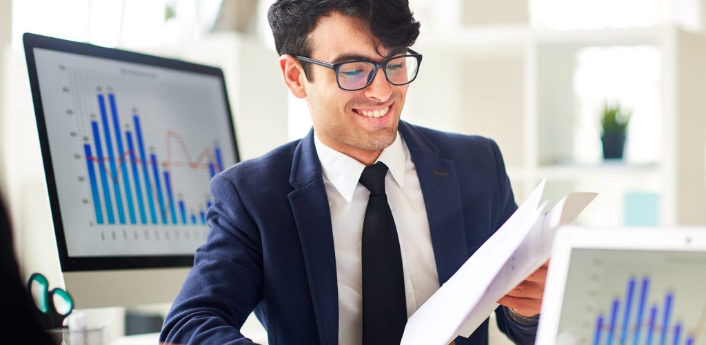 Young financier reading documents and discussing financial data with colleague